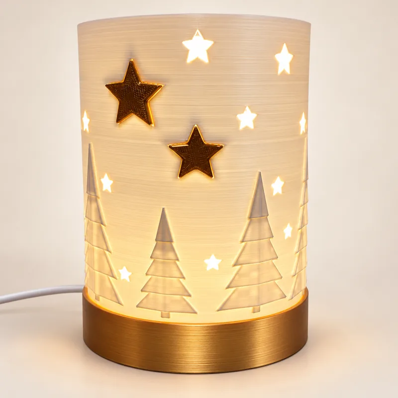 Beleuchtete Weihnachtslampe mit Tannenrelief, Sternöffnungen und goldfarbenem Sockel